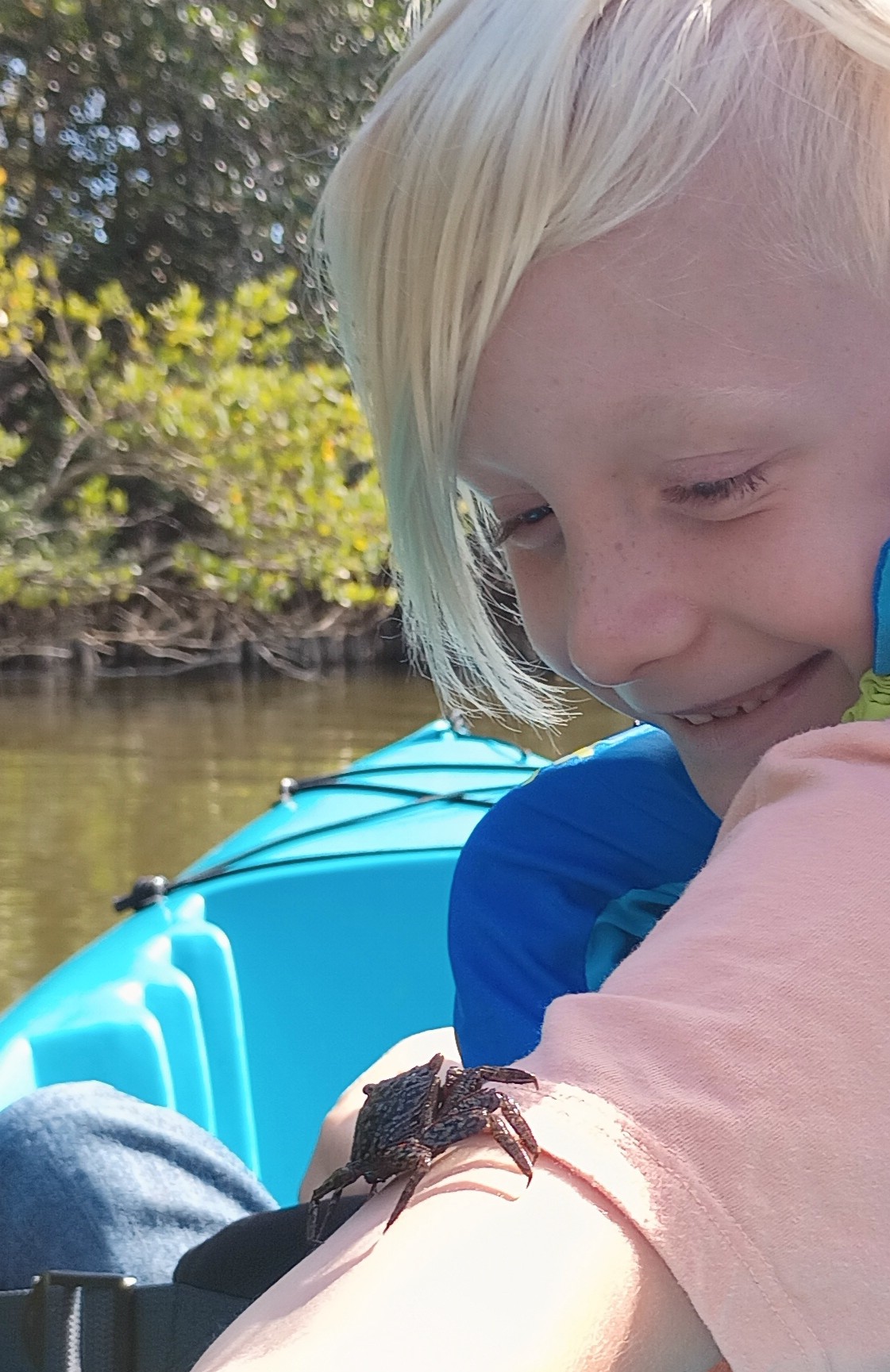 Young kayaker smiling at a crab on an outstretched arm